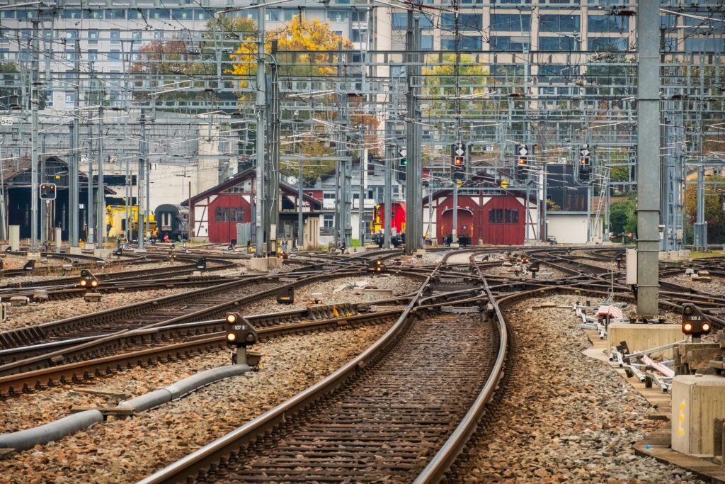 View of multiple railway tracks with signals and buildings in an urban setting during daytime.